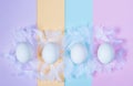 White eggs and feathers on colorful light pastel background. Happy Easter concept. Minimal style, flat lay. Close up Royalty Free Stock Photo