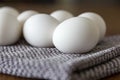 White eggs on a grey and white checkered kitchen towel upon a wooden table