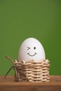 White eggs in small baskets with smiling icon and green background Royalty Free Stock Photo