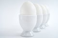 White eggs standing on egg cup isolated on white background, copy space. Row of boiled eggs in stand. Healthy food concept Royalty Free Stock Photo