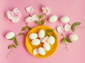 White Eggs on Yellow plate flowers On Pink Background Ester Holiday Background Concept