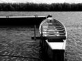 eight scull racing canoe in monochrome. anchored to a dock along a river shore.