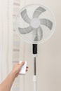 White electric fan turns on, turns off with the remote control. Hand hold electric fan remote Royalty Free Stock Photo