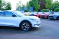 white Electric Ford Mustang Mach-E on display in parking lot of company store specializing in sale of electric vehicles,