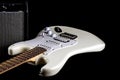 White Electric Guitar Oblique View with Amplifier on Black Royalty Free Stock Photo