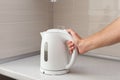 White electric Kettle in hand on the background of the kitchen Royalty Free Stock Photo