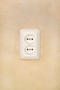 White electric outlet on gravel plaster. Royalty Free Stock Photo