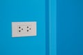 White electric outlet mounted on blue wall Royalty Free Stock Photo