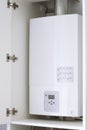 White electric water heater with electronic panel mounted in a kitchen cabinet Royalty Free Stock Photo