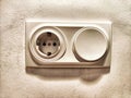 A white electrical outlet and light switch mounted on a textured wall Royalty Free Stock Photo