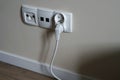 A white electrical outlet on the wall in the room. An electric plug with a cable in the socket. Royalty Free Stock Photo