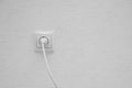 White electrical plug in the electric socket on a wall. Royalty Free Stock Photo