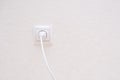 White electrical plug in the electric socket on a wall. Royalty Free Stock Photo
