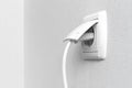 White electrical plug in the electric socket on a wall, interior photo Royalty Free Stock Photo