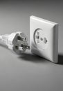 White electrical plug and socket on a gray background. The plug features two round Royalty Free Stock Photo
