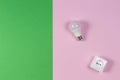 White electrical power socket and light lamp bulb on green and light pink background. Top view Royalty Free Stock Photo