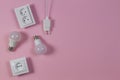 White electrical power sockets, power plugs, light lamp bulbs on light pink background. Top view Royalty Free Stock Photo