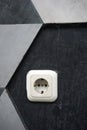 white electrical socket mounted on a gray and black geometric patterned wall Royalty Free Stock Photo