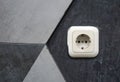 white electrical socket mounted on a gray and black geometric patterned wall Royalty Free Stock Photo