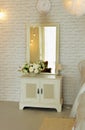 White elegant bedside table with square mirror located in bedroom Royalty Free Stock Photo