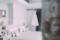 White elegant bridal dress hanging on a wooden hanger in luxury hotel room in minimalist style