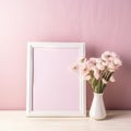 White empty blank photoframe with copy space for text or picture standing on table near vase with pink flowers