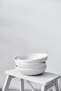 White empty ceramic plates stand in a pile stand on a wooden stool, kitchen equipment.