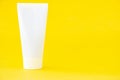 White empty cosmetic tube and green leaf of monstera on a yellow background. Blank label for branding marketing. Beauty and spa Royalty Free Stock Photo