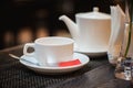 White empty cup and spoon for tea and red tea bag with teapot in Royalty Free Stock Photo