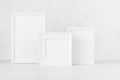 White empty different photo frames standing on white wood table in simplicity delicate modern minimal soft light interior. Royalty Free Stock Photo