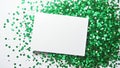 White empty greeting card over scattered green sequins, glitter and confetti isolated on white background with blank Royalty Free Stock Photo