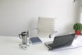 White empty office with chair, plants, ready to working day on laptop, cell phone, notebook, glasses and coffee in thermos Royalty Free Stock Photo