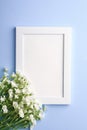 White empty photo frame mockup with mouse-ear chickweed flowers on blue background Royalty Free Stock Photo