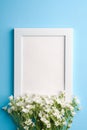 White empty photo frame mockup with mouse-ear chickweed flowers on blue background Royalty Free Stock Photo