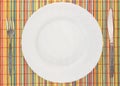 White empty plate with fork and knife on colorful placemat Royalty Free Stock Photo