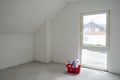 White,empty,ready-to-paint room with attic ceiling,French window,gray concrete floor.Red basket with cleaners.Copy space Royalty Free Stock Photo