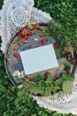 White empty sheet of paper on metallic misc with berries and flowers, white card mockup on natural background