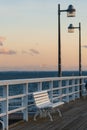 white empty wooden bench on pier by sea or ocean water, tranquility and serenity concept, calm sunset scene Royalty Free Stock Photo