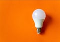 White energy saving light bulb on an orange background with copy space. LED white bulb Royalty Free Stock Photo