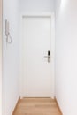 White entrance door to an apartment with metal handle and an electronic lock in center of white bright hallway with Royalty Free Stock Photo