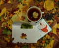 A white envelope with a beautiful mulberry leaf and a card with hearts lie next to a cup of fresh tea Royalty Free Stock Photo