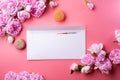 White envelope with card around roses and macaroons against pink background. life style concept