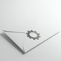 White envelope with a dark gray gear icon printed on it, positioned on a light Royalty Free Stock Photo