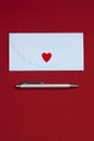 White envelope isolated with a felted heart and a silver pen. Valentine`s or Wedding`s day postcard concept. Royalty Free Stock Photo