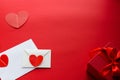 White envelope, letter and red hearts lie on a red background. On the right is a red gift box tied with a satin ribbon. Love Royalty Free Stock Photo