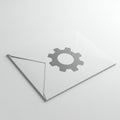 A white envelope is placed on a flat surface, featuring a gray gear icon printed on the Royalty Free Stock Photo