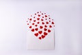White envelope with red small paper hearts on white background. Valentine's Day, love concept. Copy space.