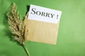 white envelope with sorry concept and reeds plant on green background Royalty Free Stock Photo