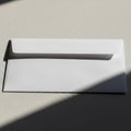 White envelope on a textured surface, partially shaded by light. The envelope is sealed, with Royalty Free Stock Photo