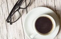 White espresso Cup and black stylish glasses on wooden background, top view, business concept pause